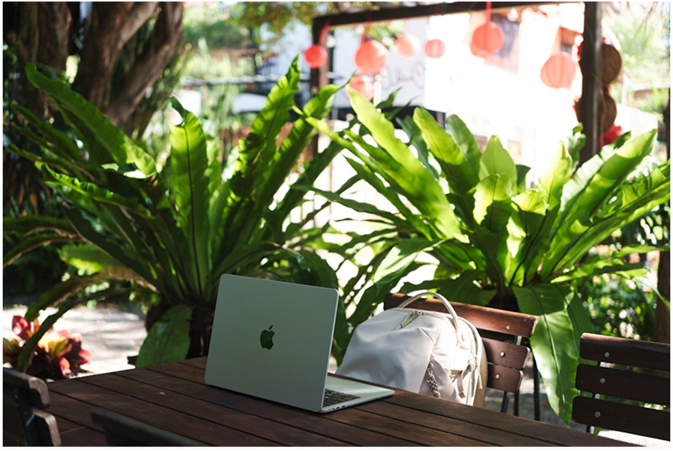 Laptop on a table surrounded by greenery